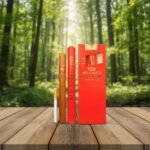 ซิการ์ Villiger Red Tube Vanilla บรรจุในหลอดอลูมิเนียมสีแดง พร้อมตัวมวนและกล่อง วางบนโต๊ะไม้กลางป่า